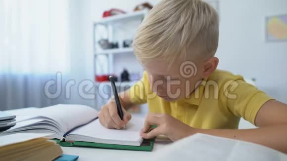 聪明的男孩子做作业在笔记本上写字教育和知识视频的预览图
