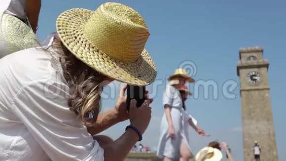 戴着草帽的年轻人拿着智能手机给一群女孩拍照视频的预览图