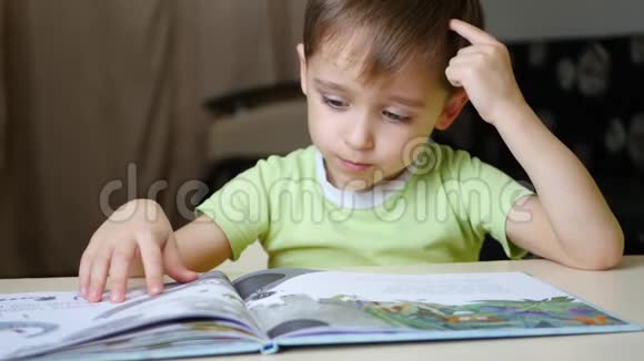 这孩子坐在家里的桌子旁沉思地读着一本书视频的预览图