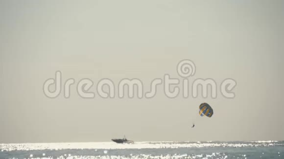 日落时分在海岸上飞行的黄蓝色降落伞夏天乘降落伞在新鲜空气中乘船飞行休息休息视频的预览图