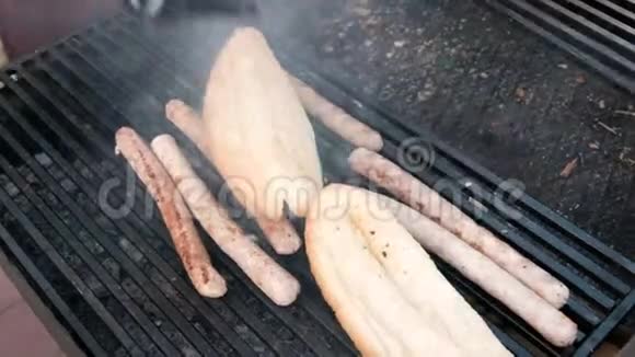 男人用钳子把热狗放进面包卷里一个穿着黑手套的街头厨师温暖香肠和面包视频的预览图