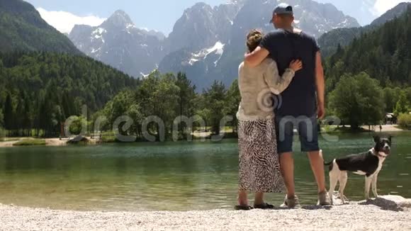 爱的夫妇在美丽的山湖岸边休息一男一女欣赏这座美丽的山视频的预览图