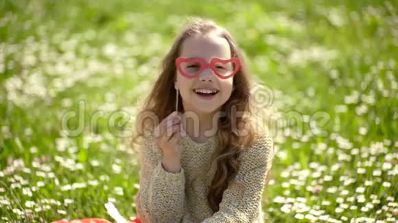 女孩坐在草地上绿色的背景小女孩在户外休闲最佳度假理念儿童假视频的预览图