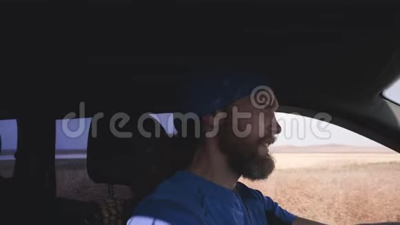 快乐的留着胡子的人在乡村风景中开车司机用手探出侧窗视频的预览图