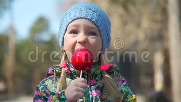 小女孩吃焦糖苹果的特写镜头视频的预览图