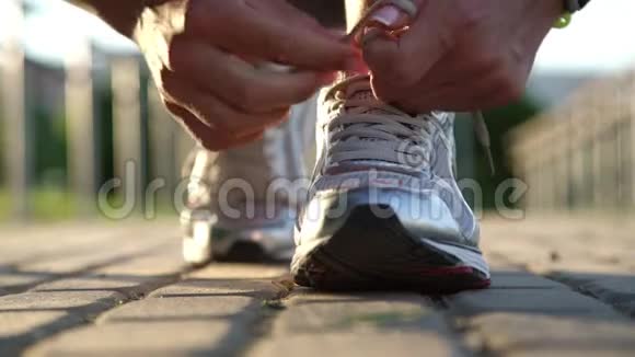年轻健康的女士双手在灰色的道路上系运动鞋鞋带视频的预览图