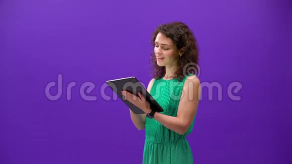 Curly女孩在一个紫色背景的手中玩一个新的I垫游戏视频的预览图