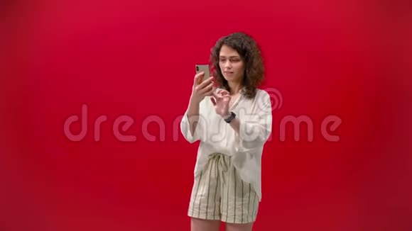 Curly女孩在一个红色背景的手机上玩游戏视频的预览图