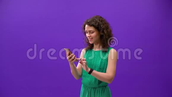 Curly女孩在一个紫色背景的手机上玩游戏视频的预览图