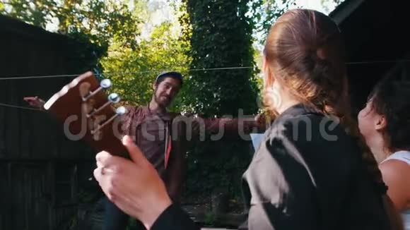 一个女人在玩巴拉莱卡一个男人在乡间别墅附近跳舞阳光明媚视频的预览图