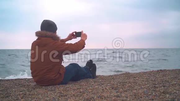 穿着夹克坐在沙滩长椅上的人博客视频的预览图