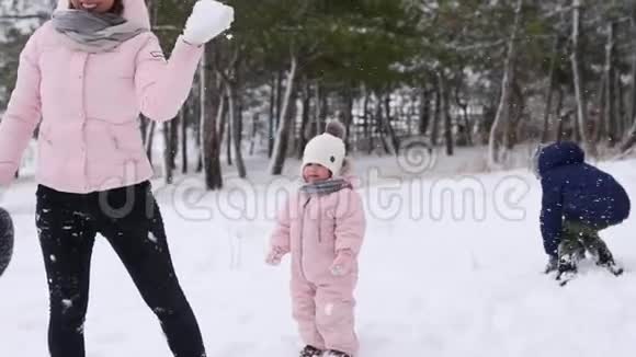 爸爸妈妈儿子和小女儿在下雪天在树林里玩雪球友好的时尚家庭乐趣视频的预览图