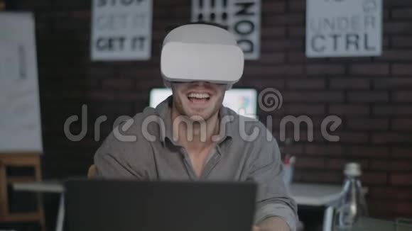 笑的男人在黑暗的办公室里看虚拟现实眼镜里的视频视频的预览图
