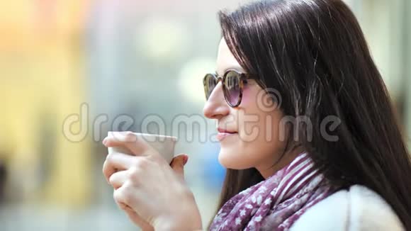 打扮时尚微笑漂亮的女士戴着太阳镜在户外放松地喝咖啡视频的预览图