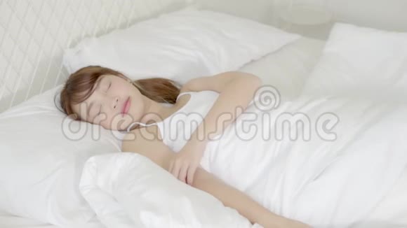美丽的亚洲年轻女子早上醒来舒展筋骨坐在卧室的床上起床视频的预览图