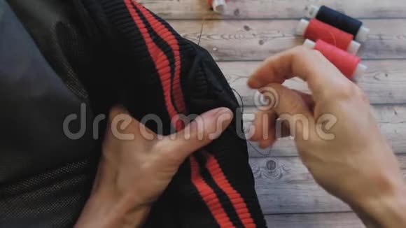 女性用手用针线将衣服上的特写镜头缝合视频的预览图