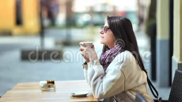 放松时尚的年轻女性在街边的咖啡馆里享受休息喝热咖啡视频的预览图
