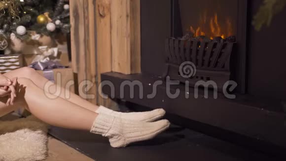 穿圣诞袜子的女孩靠近壁炉女人在家放松寒假圣诞节及新年概念视频的预览图
