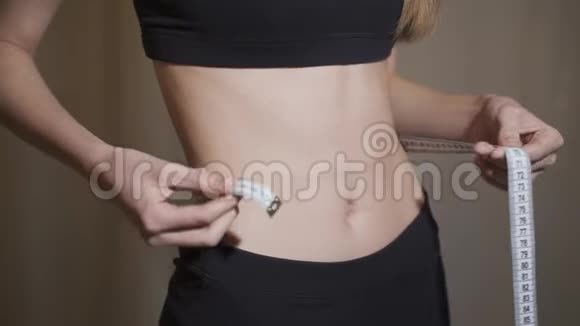 一个年轻苗条的女孩测量她腰部的体积概念厌食症消瘦视频的预览图