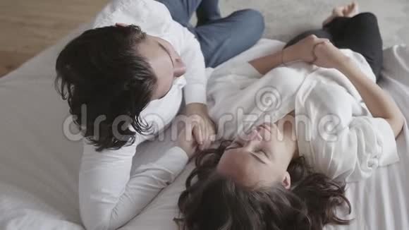 幸福的年轻夫妇躺在床上谈特写那个男人用手遮住了他女朋友的眼睛投标视频的预览图