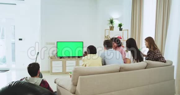 宽敞的客厅在沙发上大公司在电视上看着一部绿色的电影他们吃一些零食和视频的预览图