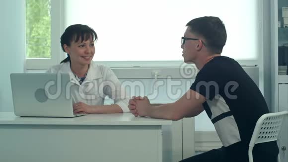 微笑女医生在她的办公室里听男病人说话视频的预览图