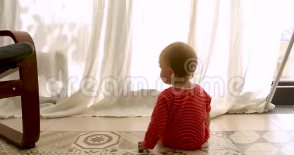 婴儿坐在靠近窗户的地板上视频的预览图
