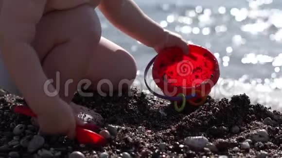 一个小男孩在沙滩上用铲子慢慢地往桶里倒沙子视频的预览图