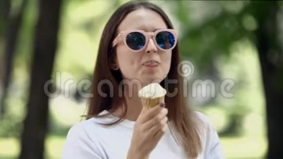 年轻女子在夏日阳光下在户外吃冰激凌戴着镜面太阳镜享受假期高清视频的预览图