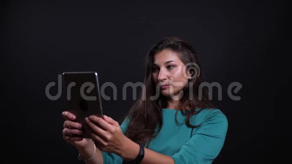 年轻漂亮的黑发女性在电话上打视频电话时愉快地与背景交谈的特写照片视频的预览图