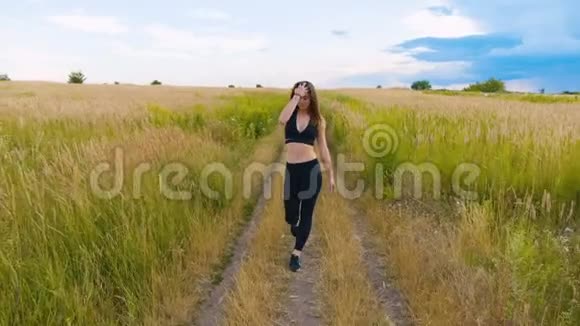 运动青年女子在美丽的田野上走在乡间的路上户外健身用定心丸射击视频的预览图