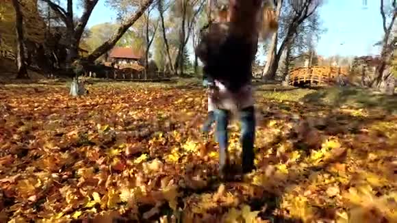 活泼的妈妈带着孩子在公园秋叶之间玩得开心视频的预览图