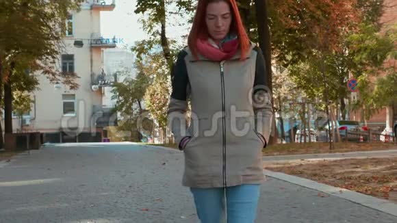 穿着夹克的年轻漂亮的红头发女人正沿街走着视频的预览图