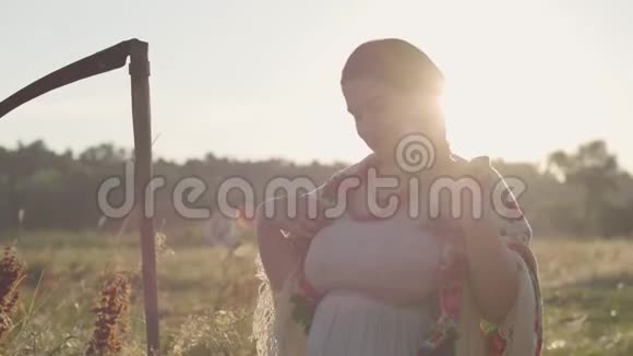 一幅美丽丰满的女人的肖像头上戴着一条披巾阳光洒在绿色的夏日田野上视频的预览图