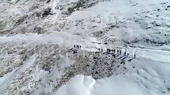 登山者在冬雪中在山岩上徒步旅行的剪影空中观景视频的预览图