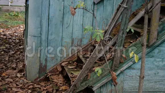 废弃的毁坏的旧木屋楼梯和门用风化油漆剥落的枯叶特写镜头视频的预览图
