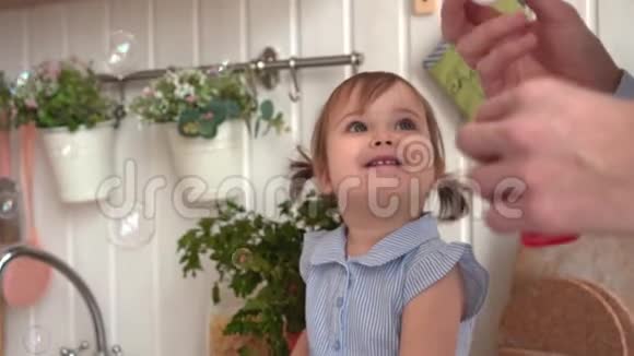 幸福的一家人在厨房里女儿上爸爸充气肥皂泡视频的预览图