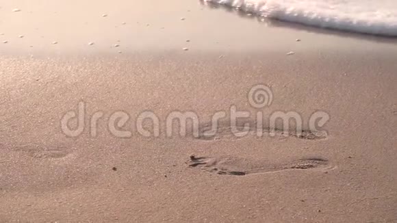 在潮湿的沙子上脚印洗去波浪这个地方适合脚视频的预览图