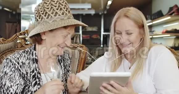 年长的母亲和成熟的女儿在平板电脑上听音乐很开心视频的预览图