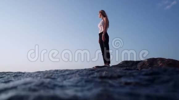 风吹在一个女孩身上吹在海里的石头上溅到相机里泡沫从海浪中涌出视频的预览图