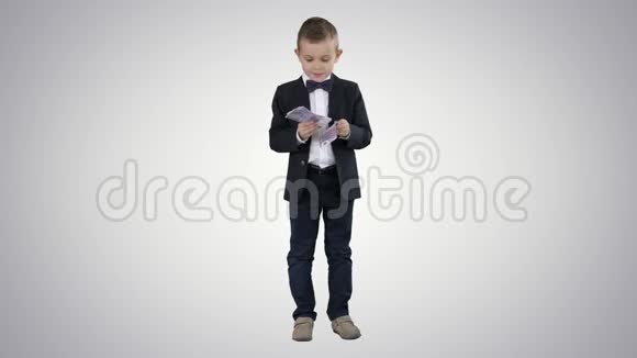 穿西装的小男孩在梯度背景背景下数钱视频的预览图