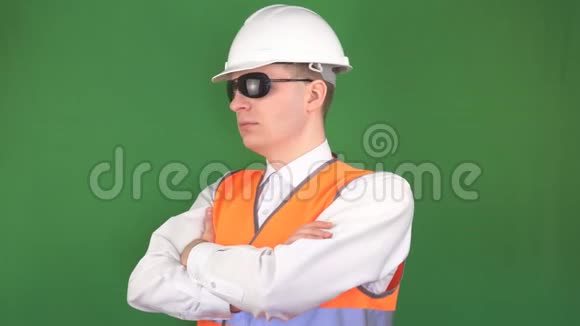 一个年轻的白种人戴着黑色眼镜戴着白色的防护头盔戴着信号灯看着摄像机绿色的视频的预览图