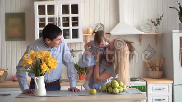 幸福的家庭在厨房里母亲抱着女儿爸爸站在附近视频的预览图