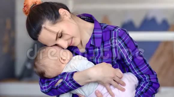 微笑的时髦年轻母亲拥抱她熟睡的小婴儿用手握着中号特写镜头视频的预览图