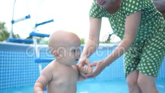 一岁的孩子在母亲的帮助下在户外充气游泳池洗澡妈妈天快乐的童年视频的预览图
