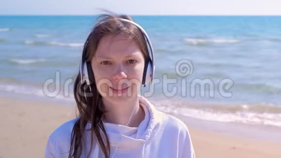 海洋背景上戴耳机的女性肖像听音乐看相机视频的预览图