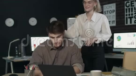 漂亮的商务女性在工作场所对年轻同事耳语视频的预览图