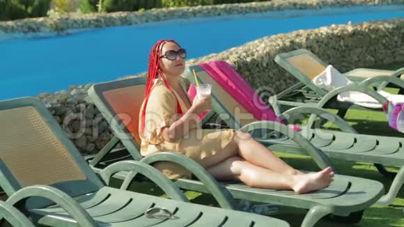 一个年轻女子在游泳池附近的躺椅上晒日光浴视频的预览图