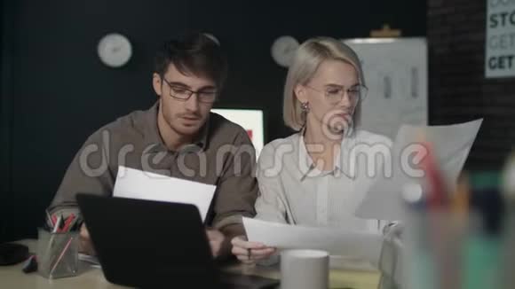 一对商务夫妇在夜班办公室使用文档数据前置笔记本电脑视频的预览图