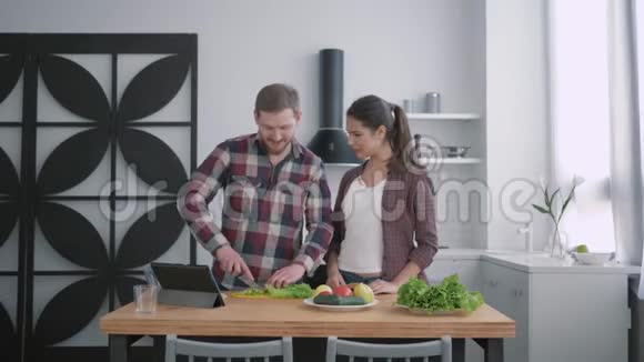 年轻家庭在厨房的肖像幸福的夫妻为早餐准备食物菜桌上有蔬菜视频的预览图